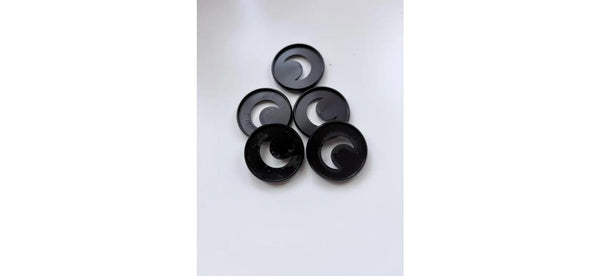 Five black planner binding discs with crescent moon cutouts arranged in a pyramid on a white background