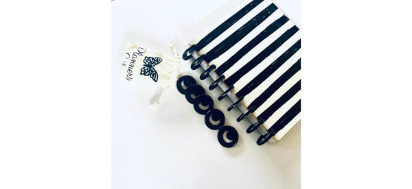 Five black crescent moon planner binding discs beside the black disc-bound spine of a black and white striped notebook, with a cream Planners Life pouch above