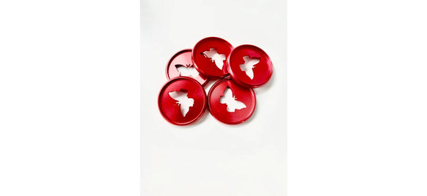 Five glossy red planner binding discs with white butterfly-shaped cutouts arranged in a loose cluster on a white background